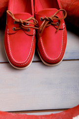 Red boat shoes on wooden background near lifebuoy. Top view. Close up.