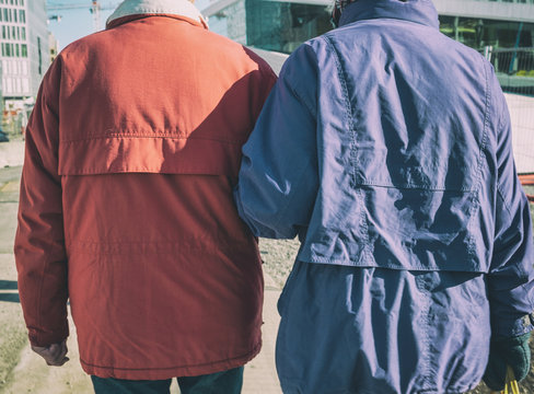 Senior couple rear cuddling arm walking in the city on winter