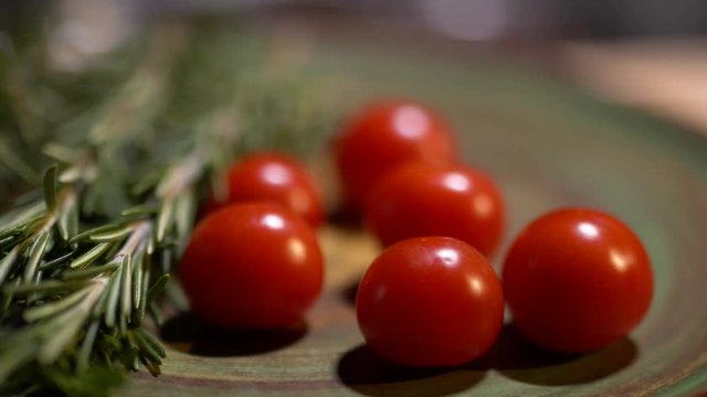 Fresh rosemary and tasty juicy red tomatoes lying on the kitchen board closeup. The camera moves from left to right.