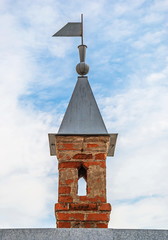 Tower-loophole with a weather vane on the roof of an old fortress