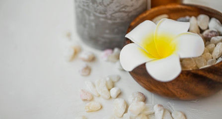 Spa frangipani flower on bamboo bowl with bath salt and candle, spa still life and wellness setting
