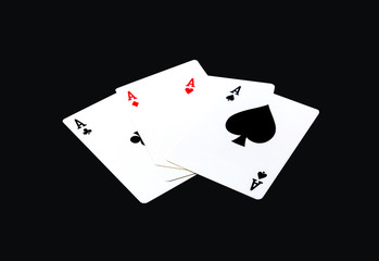 A winning poker hand of four aces playing cards suits on black.