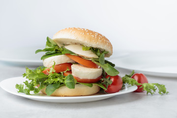 Sandwich with mozzarella, tomato and salad on the kitchen table.