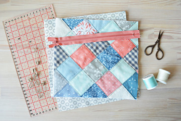 Working process: quilt, zipper, threads, retro scissors	, quilting pins and ruler on the wooden table