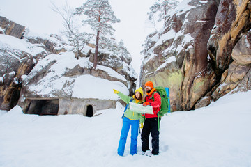 Couple of travelers man and woman with backpacks orient themselves to the terrain, study maps and navigate the route through the mountains. Travel Lifestyle and survival concept.