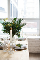 Beautiful springtime table setting with green leaves and mimosa branches, bright white table dinner decoration