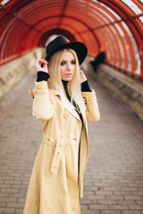 Street fashionable close up portrait of young hipster girl in yellow suit and black hat outdoors