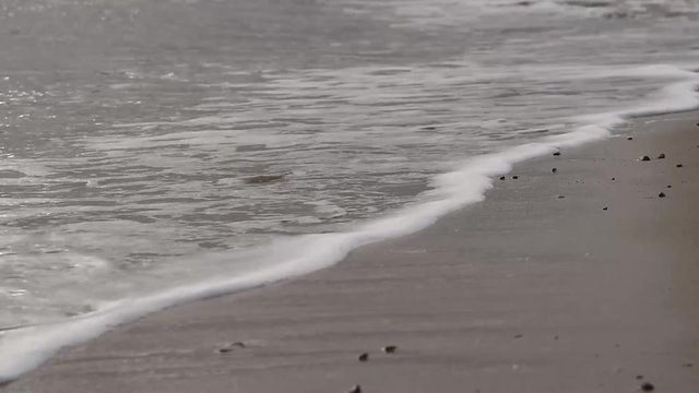 Gentle waves breaking on beach on dull winter day