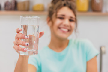 Gorgeous, beautiful, young woman holding glass of fresh water and smiling