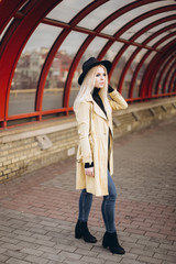 Fototapeta premium Street fashionable close up portrait of young hipster girl in yellow suit and black hat outdoors