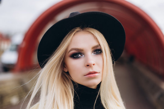 Street fashionable close up portrait of young hipster girl in yellow suit and black hat outdoors