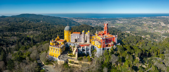 Aerial view of Pena Palace, castle stands on Sintra Mountains; monument and one of the Seven Wonders of Portugal, mixture of eclectic styles includes the Neo-Gothic, Manueline, Islamic, Renaissance - obrazy, fototapety, plakaty