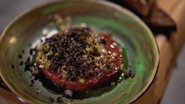 Close-up of raw tartare with the gradients of the oleic poured in a clay plate