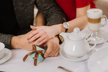 Mans and womans hands holding each other and little pressent box near