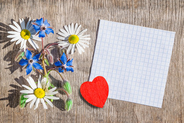 Bouquet of daisies and blue flowers of cucumber grass with heart on a wooden background vintage, background for Valentine's day, flat lay, copy space, mock up