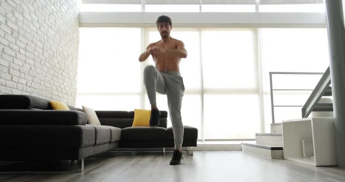 Beautiful young white man training at home. Handsome hispanic male athlete working out for crossfit, wellbeing, fitness, healthy lifestyle in domestic gym. Latino people doing high knee taps for sport