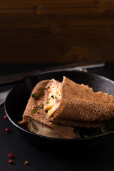 Food concept homemade Ham and Cheese Crepe in iron skillet cast on black slate background