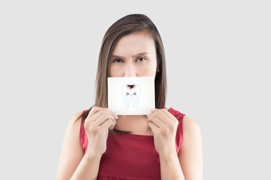 Asian woman in the red shirt holding a white paper with the caries cartoon picture of his mouth against the gray background, Have a toothache, The concept with healthcare gums and teeth