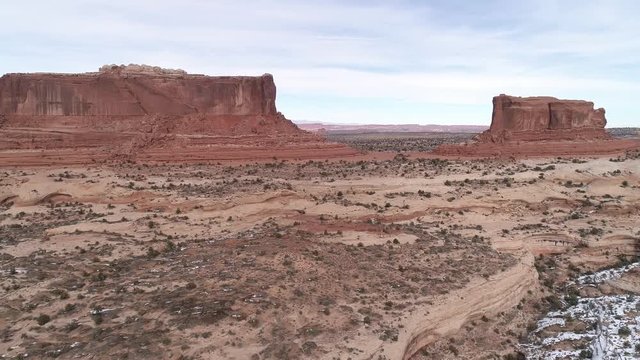 Aerial view flying away from the Monitor and the Merrimac Buttes viewing the canyons in the desert terrain near Moab Utah.
