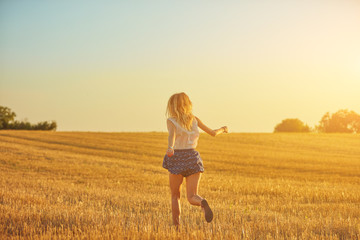 Cute young woman jumping in a wheat field.