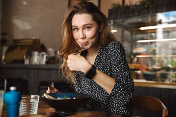 Excited beautiful young pretty woman sitting in cafe indoors have a breakfast.