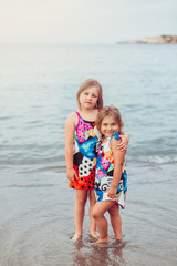 Naklejka premium Two adorable sisters playing and having fun on the beach. Childhood, vacation, joy, happiness, frienship concept