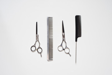 flat lay pair of hairdressing scissors and a black comb isolated on white background