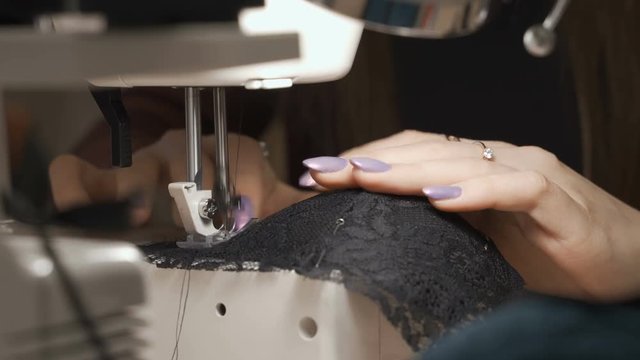 Close-up of woman's hands sewing an overlock at sewing machine.