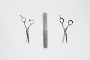 flat lay pair of hairdressing scissors and a comb isolated on white background