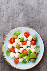 Delicious caprese salad with ripe cherry tomatoes and mini mozzarella cheese balls with fresh basil leaves.