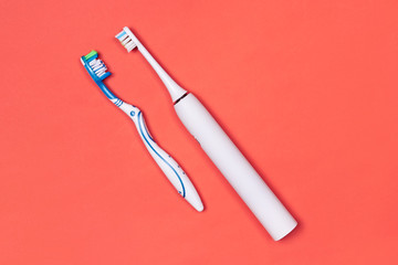 Manual and electric toothbrushes on pink coral background. Dental care