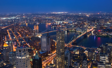 New York City's Brooklyn Bridge and Manhattan skyline illuminated at night with a full moon...
