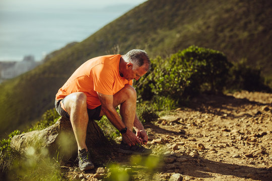 Trail runner taking a break tying shoe lace