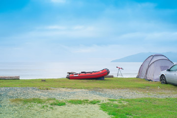 Seascape summer travel machine tent rubber boat Coastline horizon sky with clouds