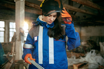 Destroying gender stereotypes. Woman wearing helmet using different male work tools. Gender...