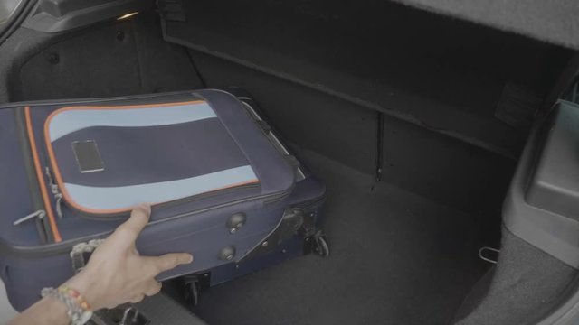 Young man hurrying loading his car trunk in a rush with travel bags worried about missing flight