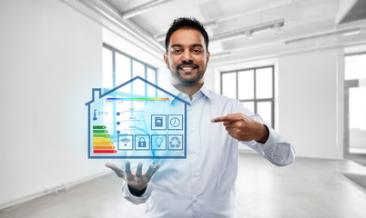 automation, internet of things and technology concept - smiling indian businessman or realtor with smart home virtual projection over empty office room background
