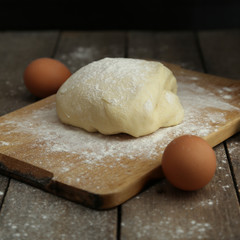 Fresh preparing dough on a cut board and wooden table. Cooking bread concept