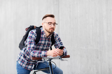 Fototapeta na wymiar travel, tourism and lifestyle - young hipster man in earphones with fixed gear bike and backpack on city street