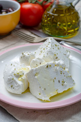 Fresh young soft white Feta cheese with olive oil on plate seasoned with dried oregano herb