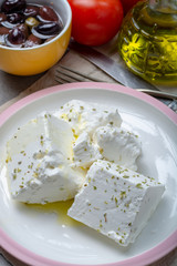 Fresh young soft white Feta cheese with olive oil on plate seasoned with dried oregano herb