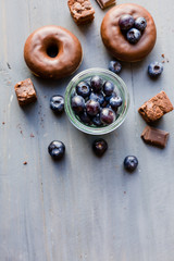 Fototapeta na wymiar Donut mit Schokoglasur und Blaubeeren auf blauen Holz
