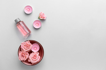 Spa composition with flowers, candles and essential oil on light background