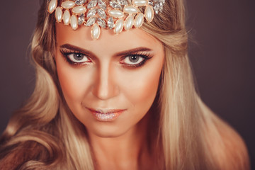 Close up portrait of gorgeous young fashionable model with long blondie hair and jewelery