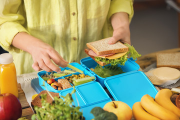 Mother preparing lunch for schoolchild at table