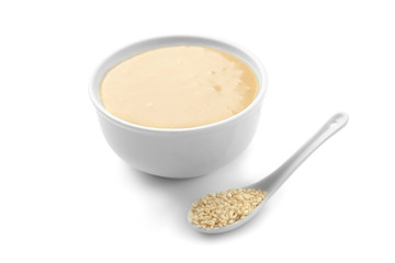 Bowl of tasty tahini with sesame seeds on white background