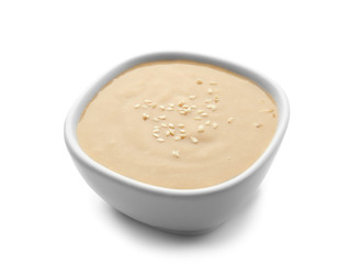 Bowl of tasty tahini on white background