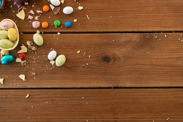 easter, sweets and confectionery concept - chocolate eggs and candy drops on wooden table