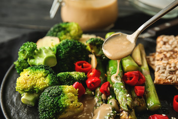 Dressing of fresh vegetables with tasty tahini on plate