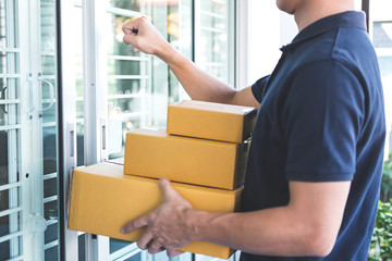 Delivery man standing with parcels in hands outdoors waiting homeowner open door, Home delivery service and working with service mind